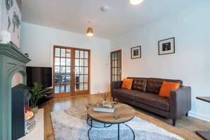 A living room with a fireplace, a brown leather sofa, a round coffee table, and a large window with a view. - 10 Mins to Aberdeen City Centre - Parking - Garden (Edinburgh)
