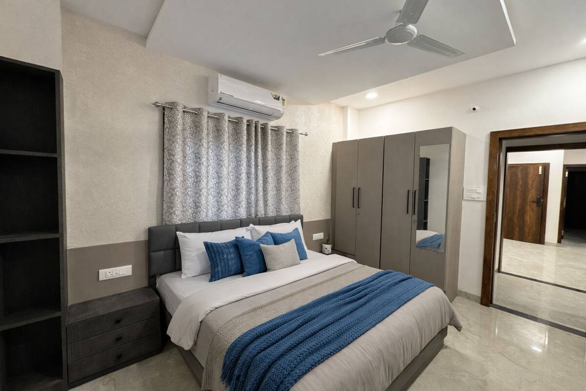 Un dormitorio moderno con cama, armario y estanterías empotradas.
