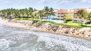 Ein Strandhotel mit Pool, Palmen und felsiger Küste.