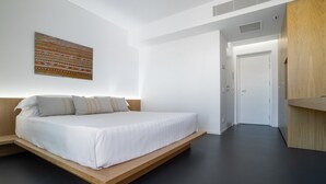 Une chambre à coucher moderne avec un lit bas sur une plateforme, une grande peinture abstraite et un design minimaliste.