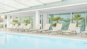 Une piscine avec des chaises longues et des plantes en pot.