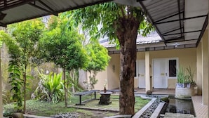 A tranquil courtyard with a water feature, surrounded by lush greenery and a traditional building. - Pojok Pas Guesthouse (Yogyakarta)