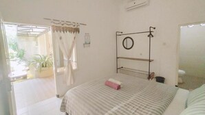 A bedroom with a bed, a window with curtains, a small shelf, and a mirror. - Pojok Pas Guesthouse (Yogyakarta)