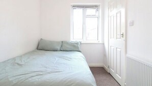 A small, bright room with a single bed, a window, and a door. - Coventry Road Studio Flat (Southampton)