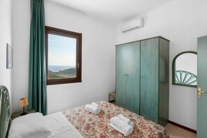 A bedroom with a bed, a wardrobe, a window with curtains, and a view of the landscape. - P.R. Club - Four-Room Velia 44 with Sea View, Private Terrace and Air Conditioning (Centola)
