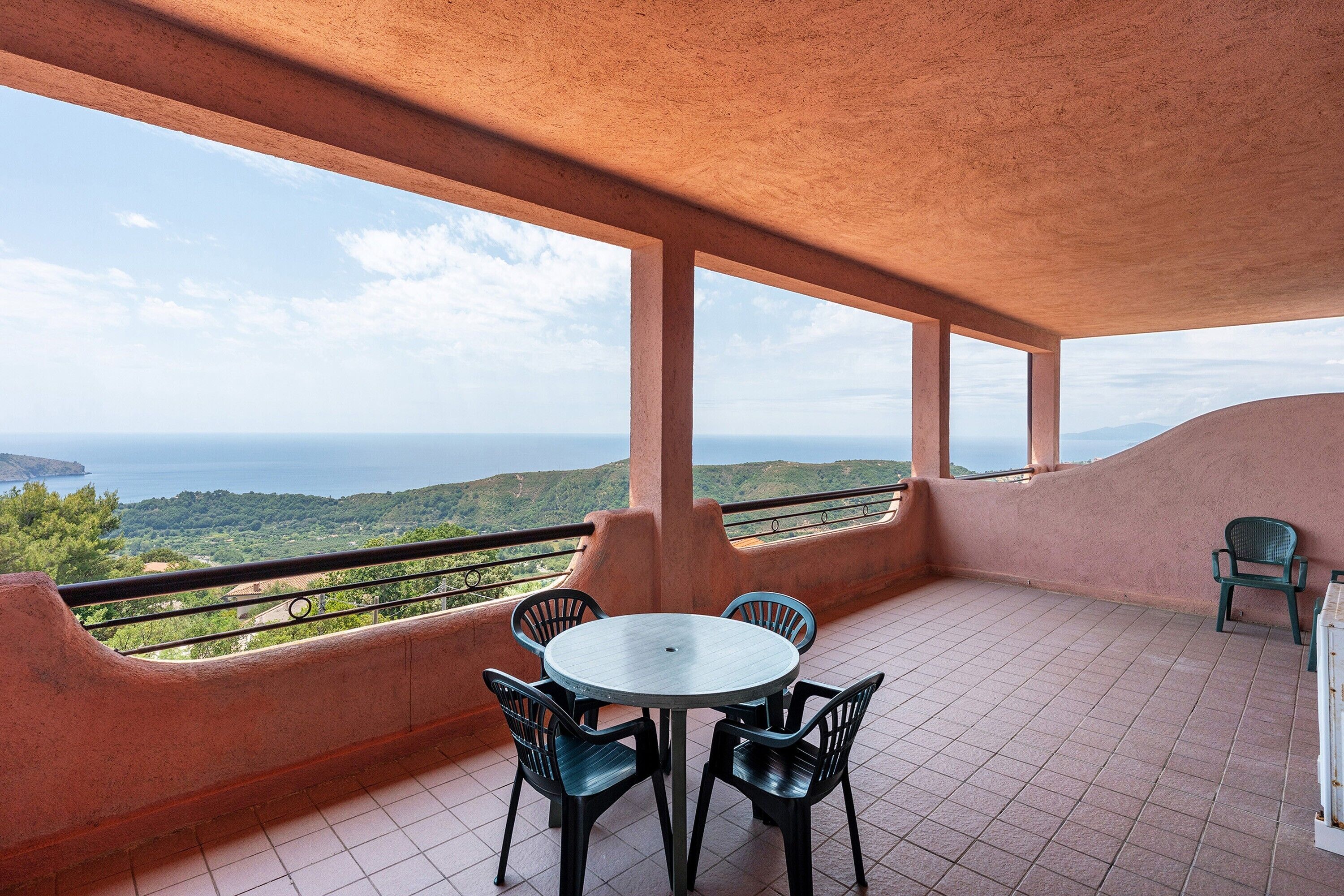 Een terras met een ronde tafel en stoelen, met uitzicht op een prachtig landschap.