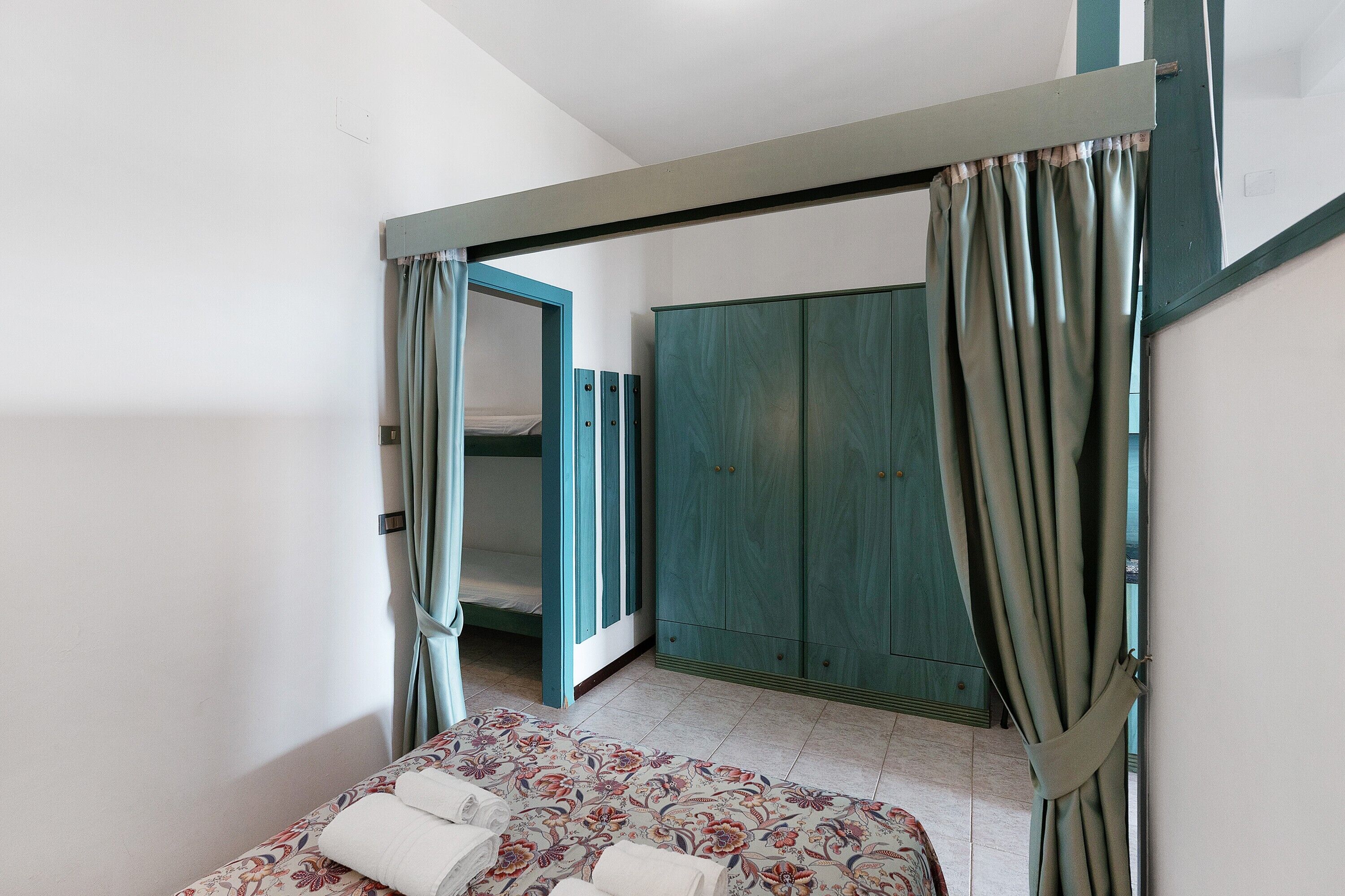 Ein Schlafzimmer mit einem Bett, einem Kleiderschrank und einem Vorhang.