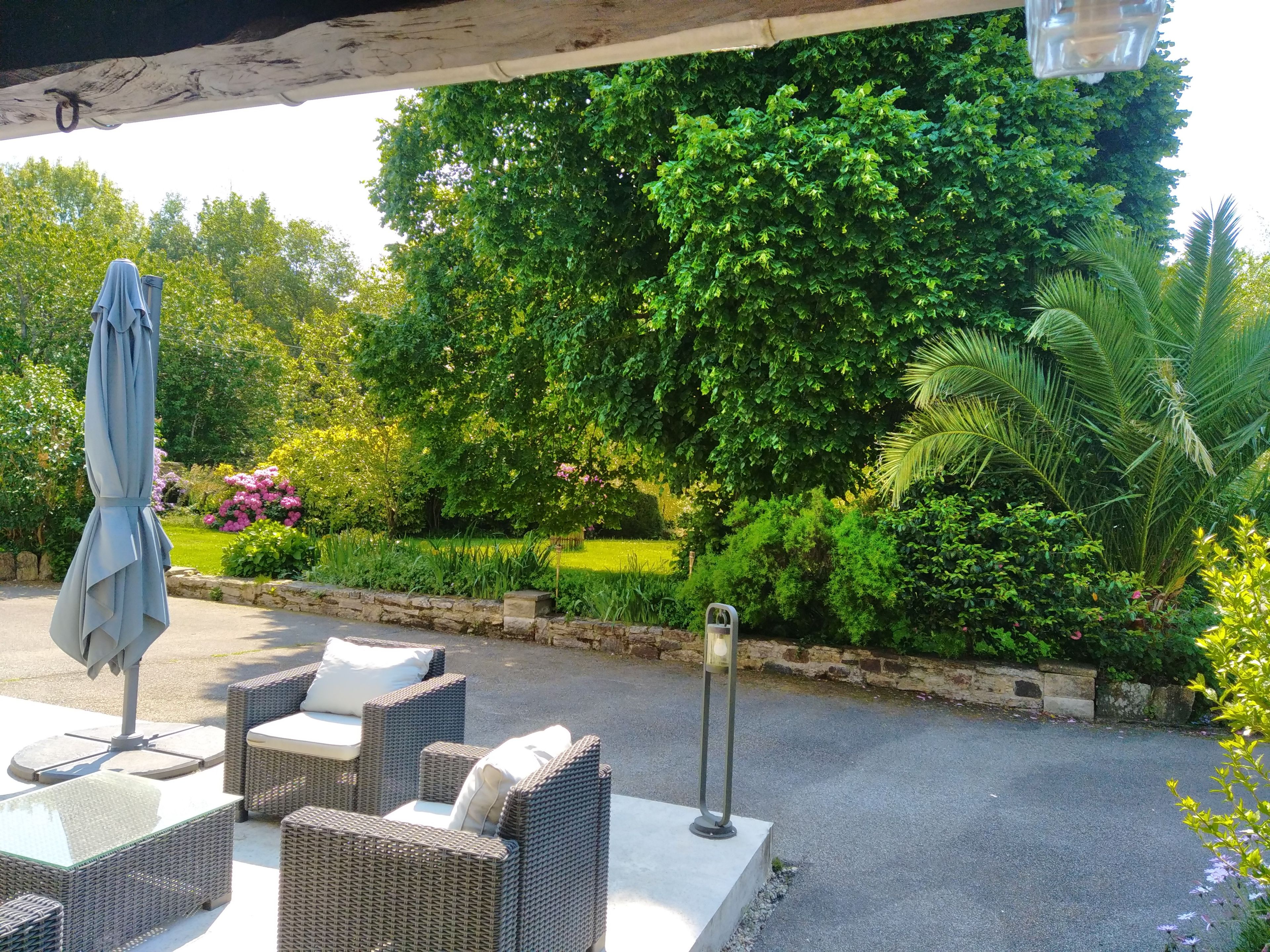 Een terras met buitenmeubilair van rieten vlechtwerk en een overdekte veranda.