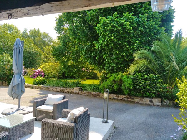 Un espace extérieur aménagé avec des meubles en osier et une terrasse couverte.