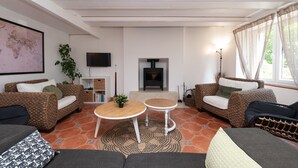 A living room with wicker furniture, a fireplace, a television, and a world map on the wall. - Family Home for 10 Guests (Bannalec)