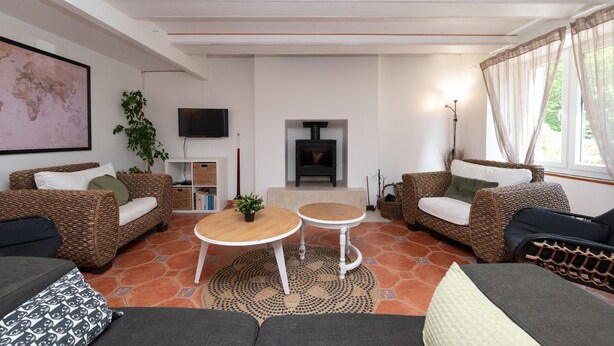 Een woonkamer met rieten meubilair, een open haard, een televisie en een wereldkaart aan de muur.