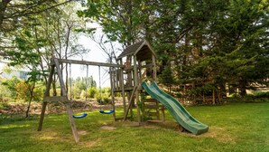 A wooden playground structure with a slide and swings. - Family Home for 10 Guests (Bannalec)