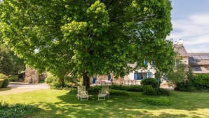 A stone building with a large tree in front, two lawn chairs, and a clear sky. - Family Home for 10 Guests (Bannalec)