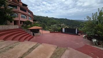 A red carpeted outdoor area with steps leading up to a building, a small kiosk, and a stage with a banner.