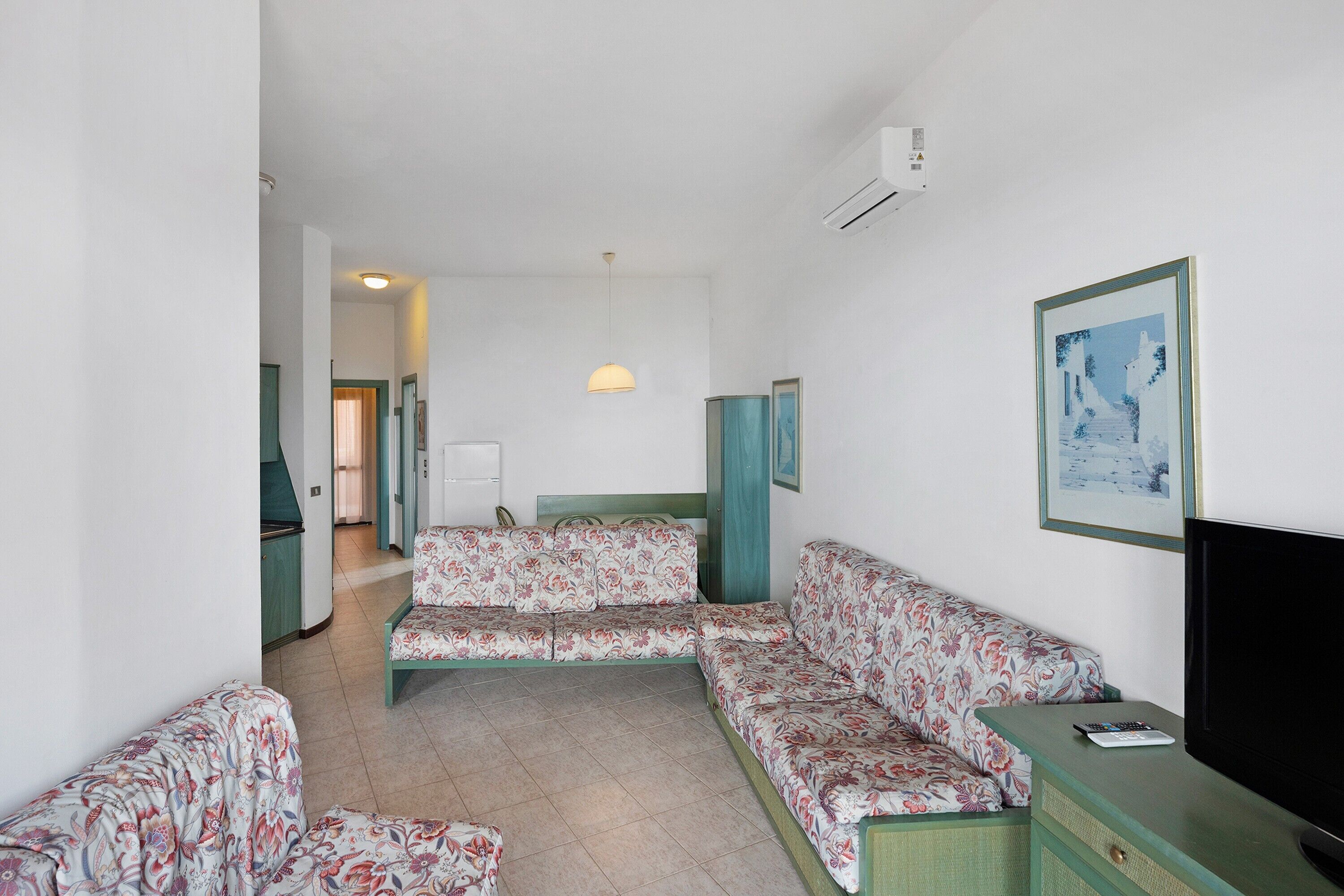 Una camera d'albergo con un divano, una televisione e un quadro appeso al muro.
