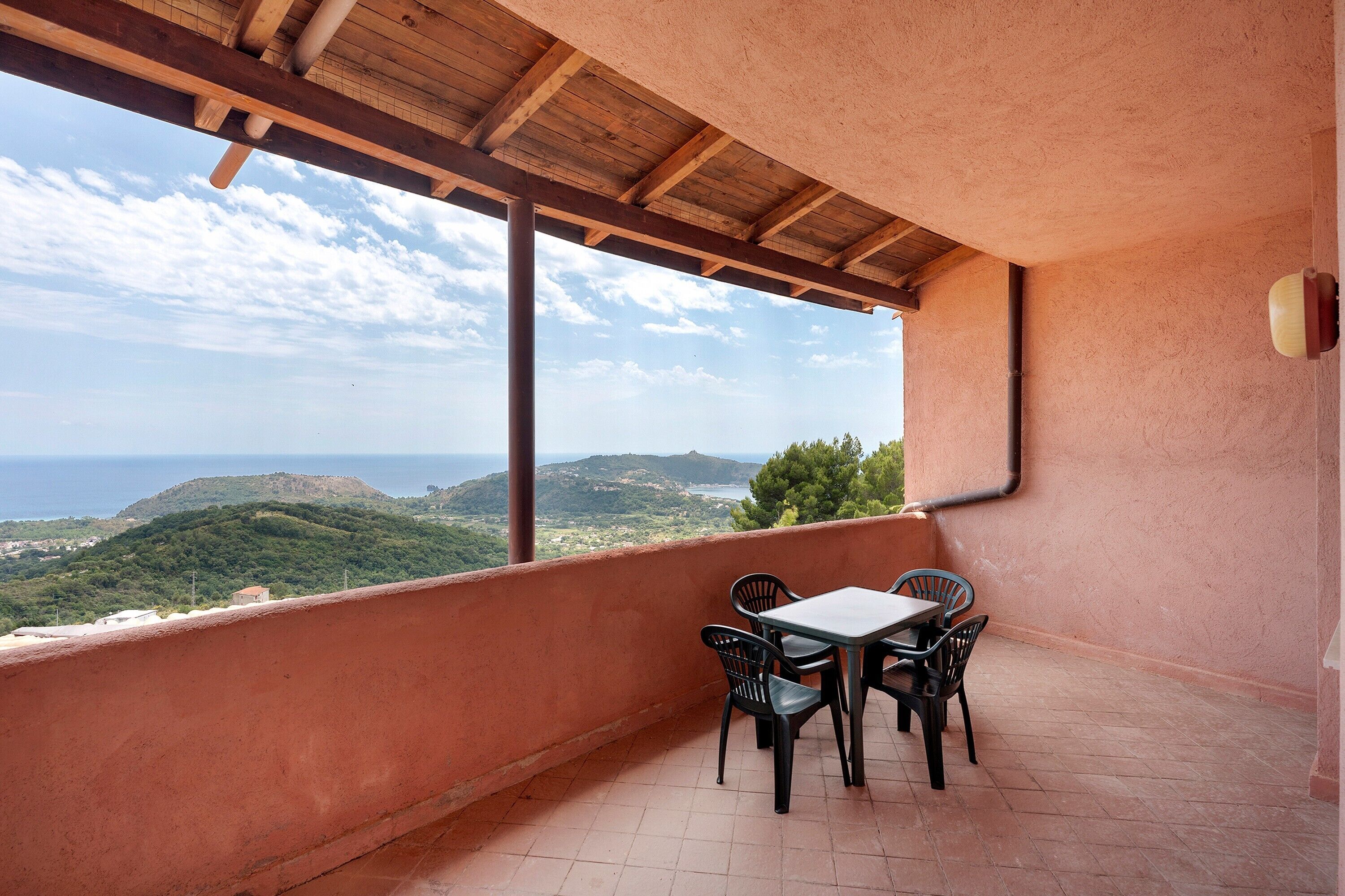 Un balcon avec une table et des chaises, une vue sur la mer et un paysage montagneux.