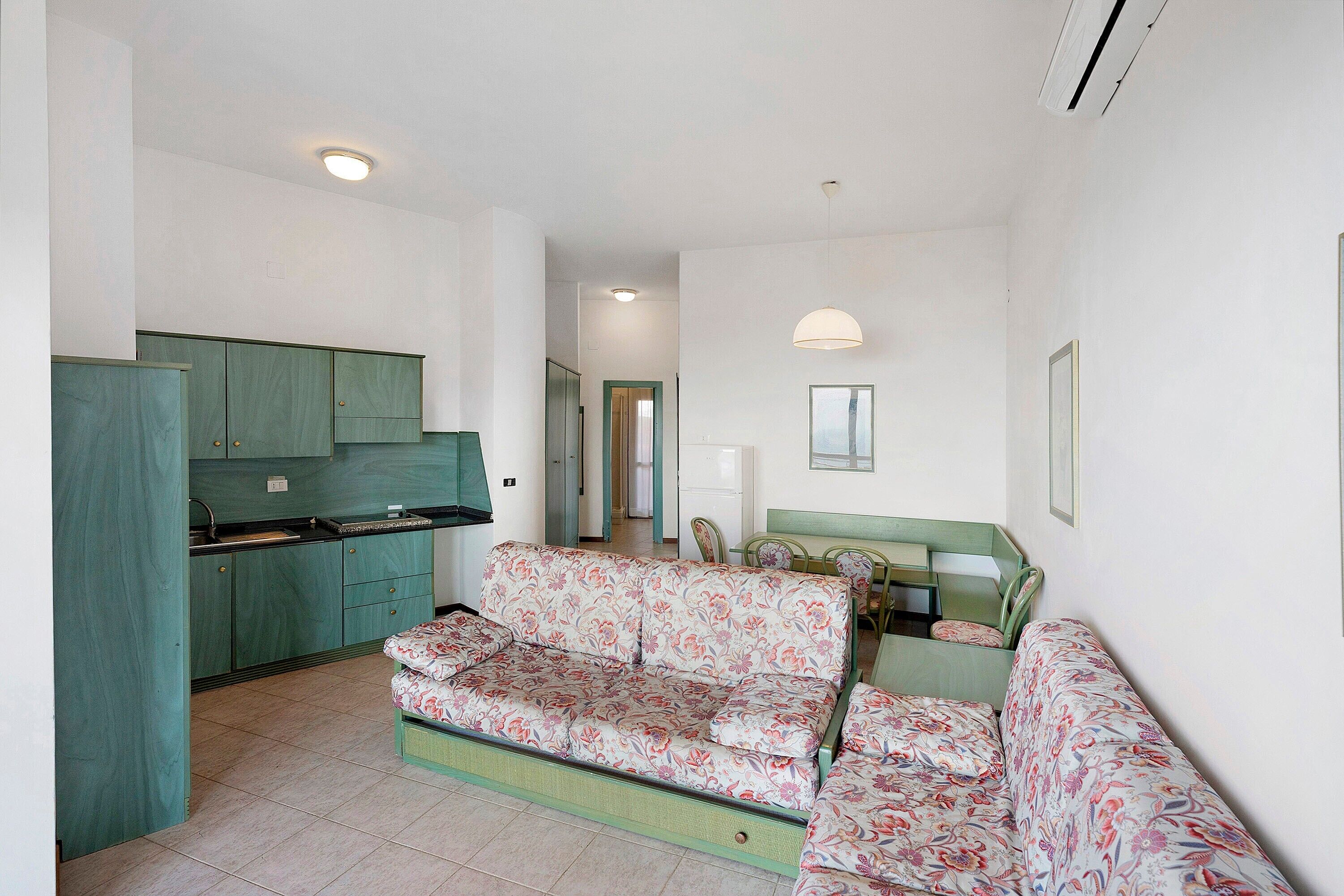 A compact living space with a kitchenette, a sofa set, and a dining area.