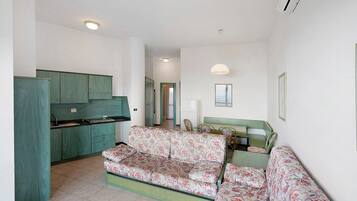 A compact living space with a kitchenette, a sofa set, and a dining area.