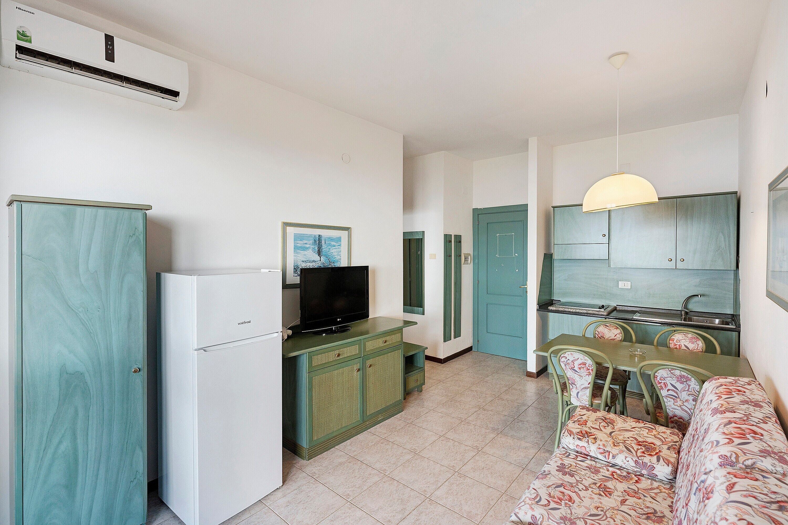 A compact living space with a kitchenette, a dining area with a table and chairs, and a sofa.