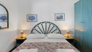 Un lit recouvert d’une couvre-lit à motifs floraux, deux lampes de chevet et deux œuvres d’art encadrées accrochées au mur.