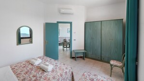 A bedroom with two beds, a wardrobe, a bench, and a mirror. - P.R. Club – Studio Molpa 15' with Sea View, Private Terrace and Air Conditioning (Centola)