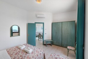 A bedroom with two beds, a wardrobe, a bench, and a mirror. - P.R. Club – Studio Molpa 15' with Sea View, Private Terrace and Air Conditioning (Centola)