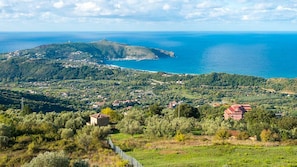 Eine Küstenlandschaft mit einem Hügel, einem kleinen Dorf und freiem Blick auf das Meer.