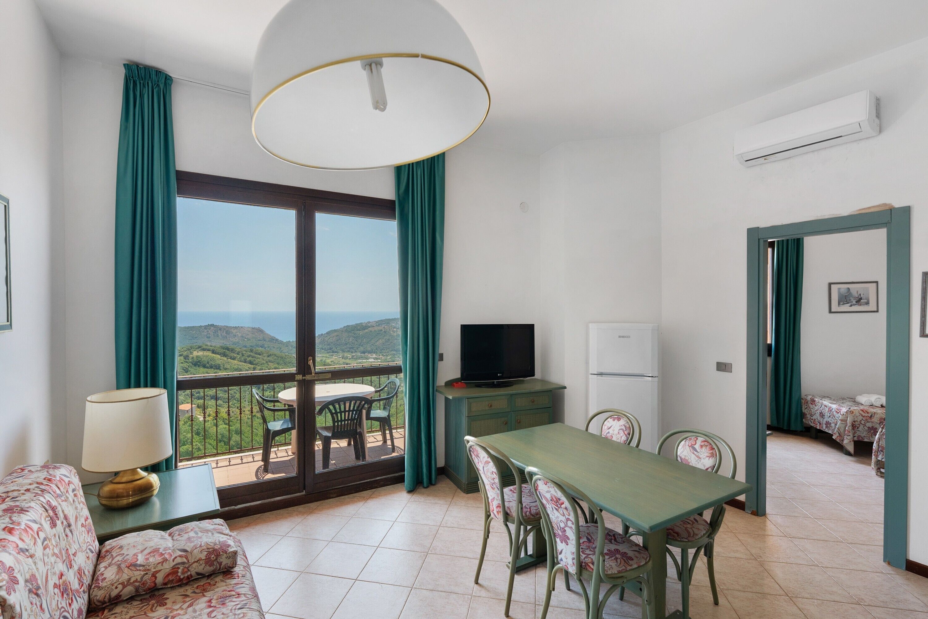 Une chambre avec balcon, un coin repas et un téléviseur.