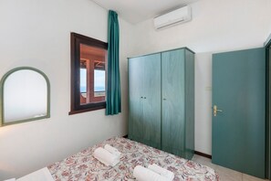 A bedroom with a bed, a wardrobe, a mirror, and a window with curtains. - P.R. Club - Studio Molpa 16 with Sea View, Private Terrace and Air Conditioning (Centola)