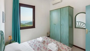 Une chambre à coucher comprenant un lit, une armoire, une fenêtre avec vue et un appareil de climatisation.