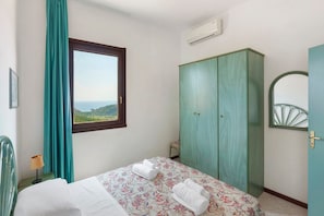 A bedroom with a bed, a wardrobe, a window with a view, and an air conditioning unit. - P.R. Club - Studio Molpa 5 with Sea View, Private Terrace and Air Conditioning (Centola)
