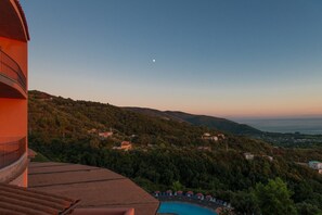 Ein Poolbereich mit Blick auf eine gebirgige Landschaft und einem sichelförmigen Mond am Himmel.