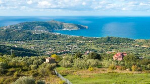 Eine Küstenlandschaft mit einem Hügel, einem kleinen Dorf und freiem Blick auf das Meer.