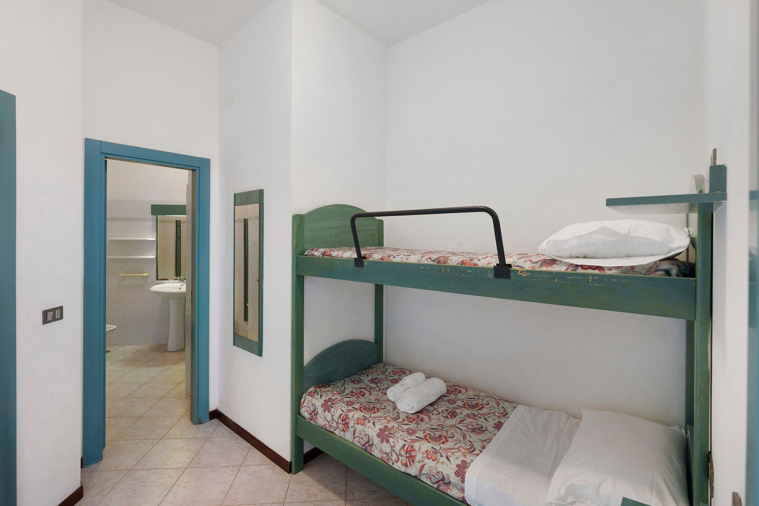 Une chambre avec des lits superposés, la salle de bain étant visible à travers une porte ouverte.