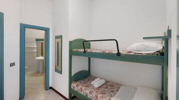 Habitación con literas y un baño visible a través de una puerta abierta.