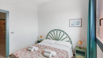 Een slaapkamer met een bed, twee nachtkastjes, een aan de muur hangend schilderij en een deur.