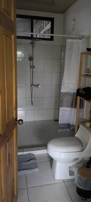 A bathroom with a shower, toilet, and a wooden door. - Aguas del Alma Welcomes you (Páramo)