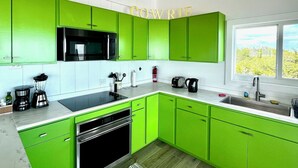 A modern kitchen with green cabinets, a black microwave, and a coffee maker. - Luxury Simplicity On The Beach, Little Exuma.  Brand new, 2 bedrooms. (little exuma, Bahamas)