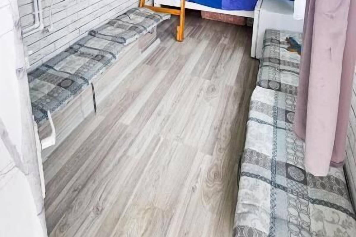Une petite pièce comprenant un lit superposé, une échelle en bois, un banc rembourré et une fenêtre avec des rideaux.