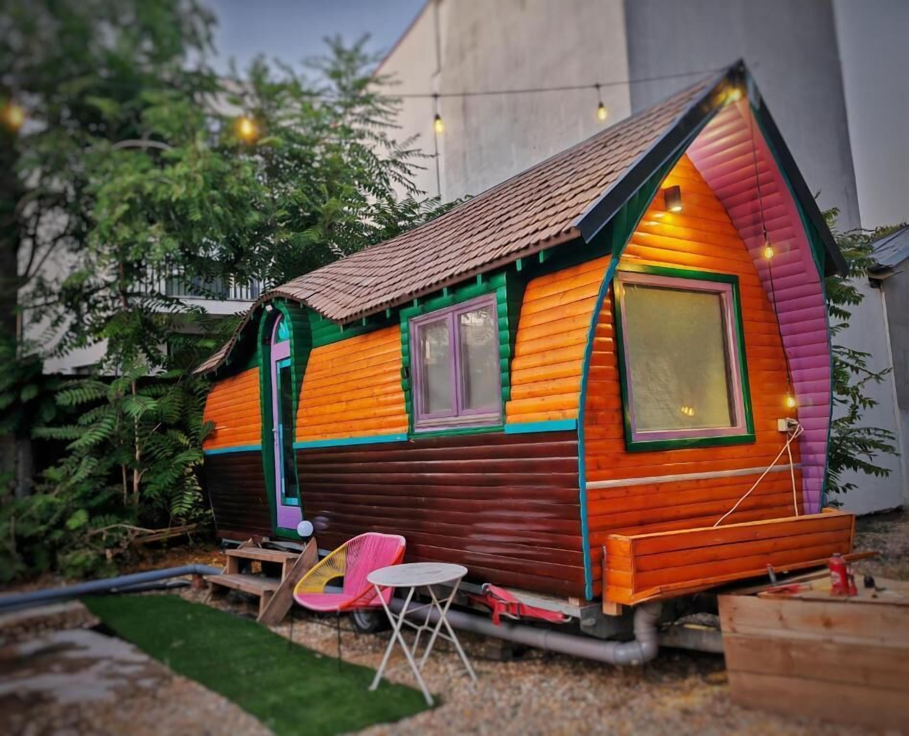 Una casa de madera colorida con techo inclinado, dos ventanas y un pequeño porche.