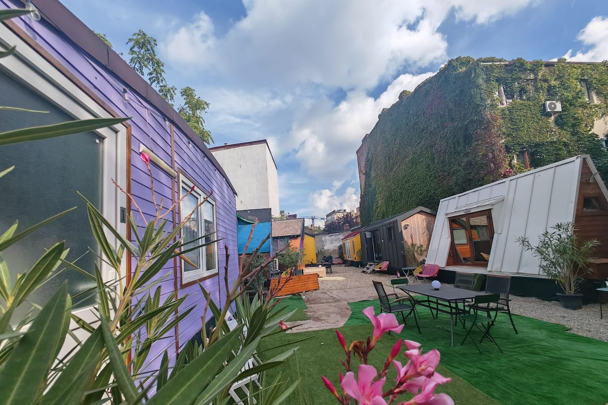 Une cour avec des mobil-homes aux couleurs vives, une pelouse verdoyante et une chaîne de montagnes en arrière-plan.