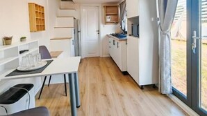 Une cuisine moderne avec des meubles blancs, un coin repas avec une table et des chaises blanches, et une grande fenêtre avec des rideaux.