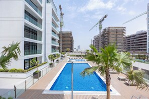 Un edificio moderno con piscina, rodeado de palmeras y un cielo despejado.