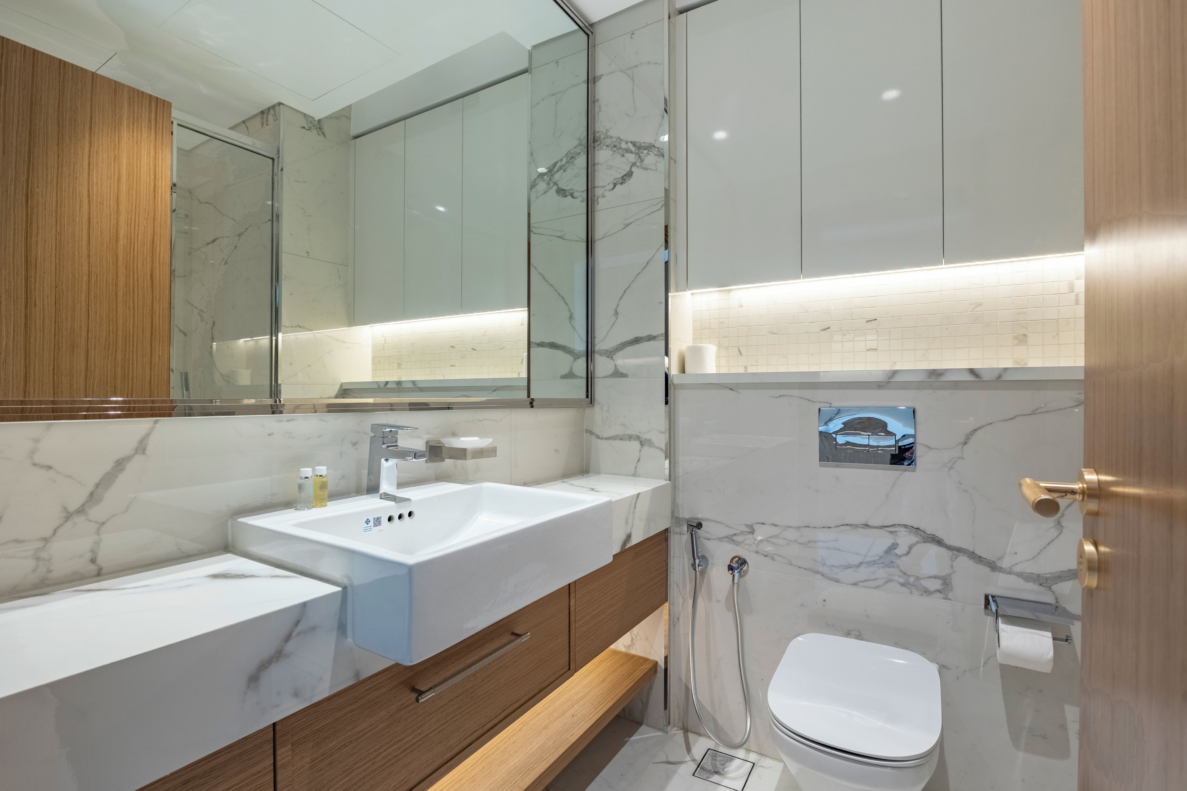 Un baño moderno con un espejo grande, dos lavamanos, una ducha y un inodoro.