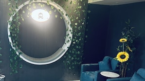 A modern interior with a circular light fixture, dark wooden paneling, and blue seating. - Hotel The Season (Ahmedabad)