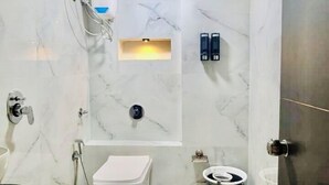 A bathroom with a toilet, bidet, and a water heater. - Hotel The Season (Ahmedabad)