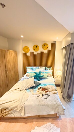Un dormitorio con cama, armario de madera y una pared decorada con caritas sonrientes.