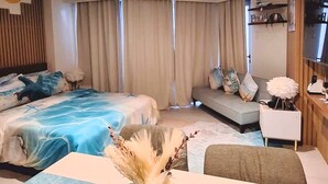 Ein modernes Hotelzimmer mit einem großen Bett, einer Couch, einem Esstisch und einer dekorativen Vase.
