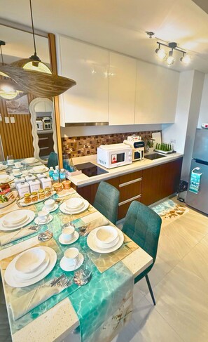 Una cocina moderna con comedor, que presenta una mesa de mármol, un ventilador de techo y un refrigerador.