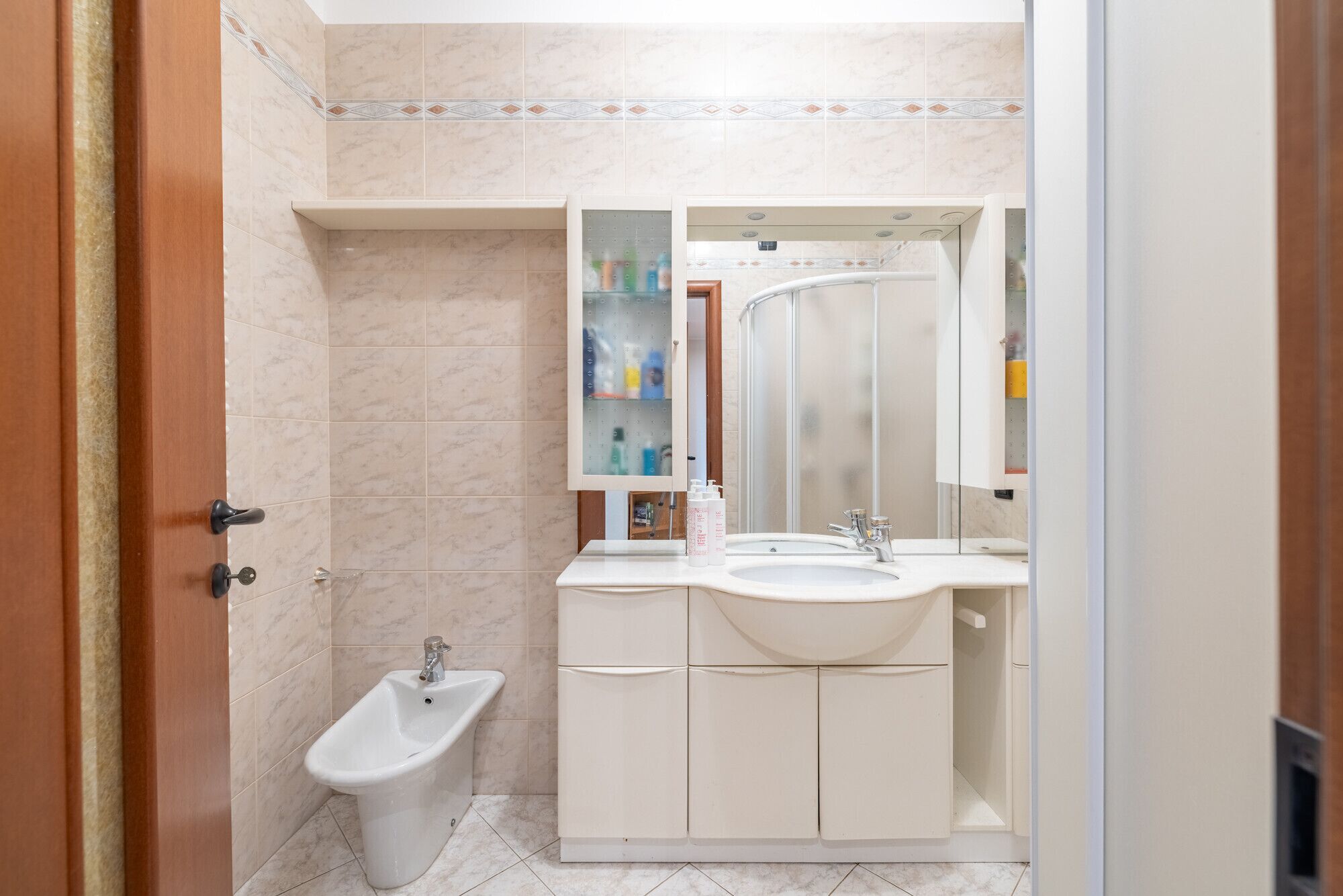 Ein Badezimmer mit einer Bidet-Funktion, einem Waschbecken und einem Spiegel.